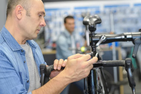 男はスポーツ ショップで購入する前に自転車をチェックします。 — ストック写真