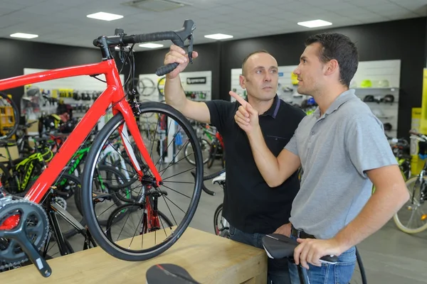 Веселий батько вибирає новий спортивний велосипед в магазині — стокове фото
