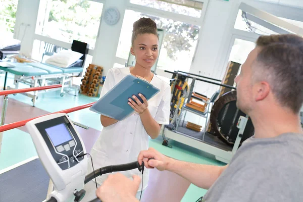 Atletisk patienten utövar på en stillastående cykel under medicinsk undersökning — Stockfoto