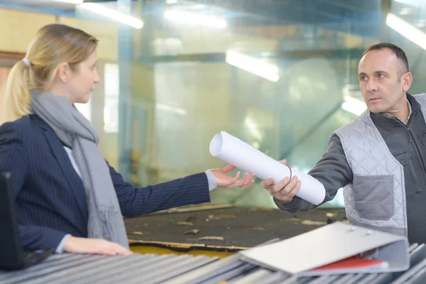 Industrial worker gives a blueprint to secretary — Stock Photo, Image