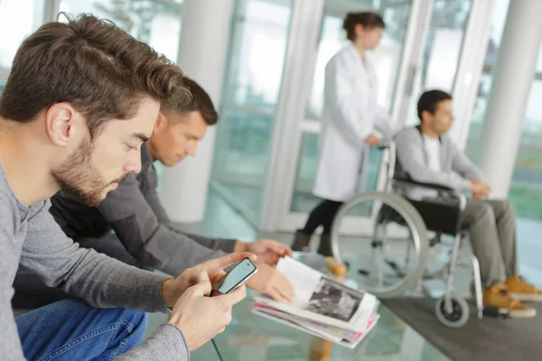 Ο άνθρωπος χρησιμοποιώντας το smartphone στο νοσοκομείο αίθουσα αναμονής — Φωτογραφία Αρχείου