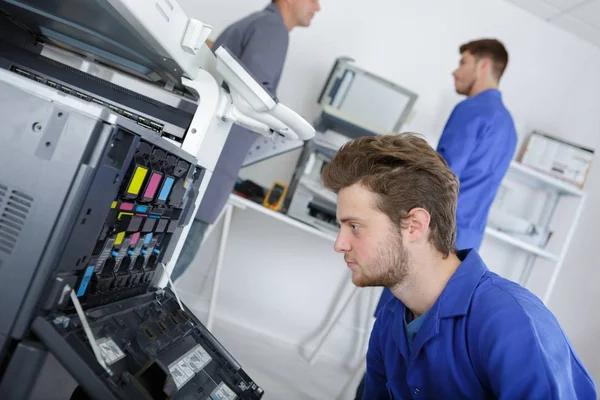 Oung técnico masculino reparando máquina fotocopiadora digital — Fotografia de Stock