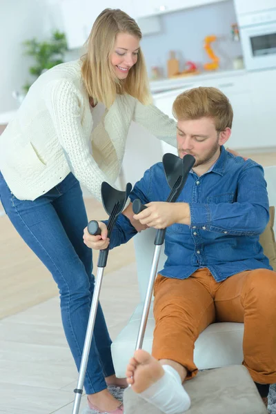 Deficiente homem em muletas com a ajuda de um amigo — Fotografia de Stock
