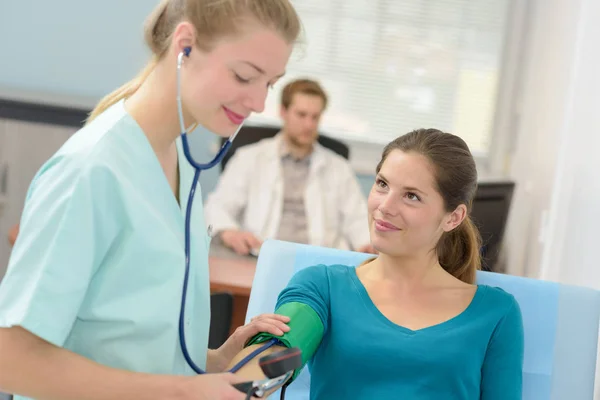 Молодая женщина-врач проверяет кровяное давление пациента — стоковое фото