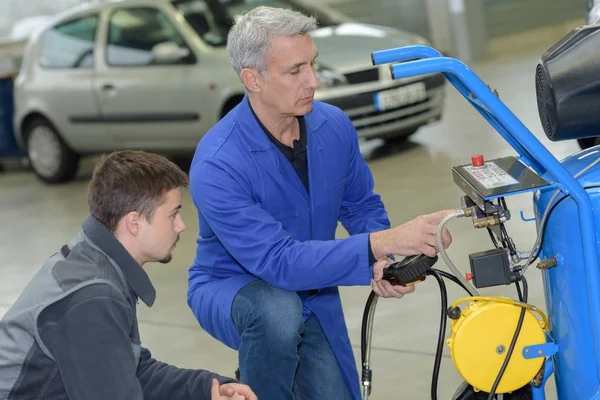 Estudiante con instructor reparando un coche durante el aprendizaje — Foto de Stock