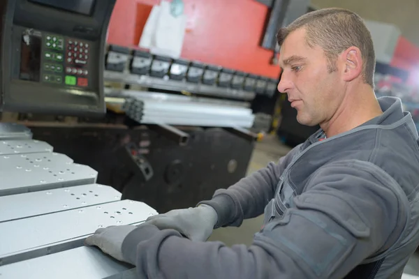 Travailleur debout devant une énorme machine industrielle — Photo