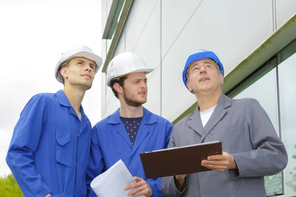 Engenheiro e construtores com chapéu duro usando tablet fora do edifício — Fotografia de Stock