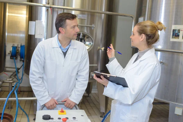 Two workers in labcoat working at a factory — Stock Photo, Image