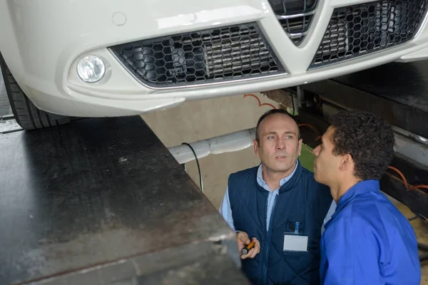 male car mechanic working under car