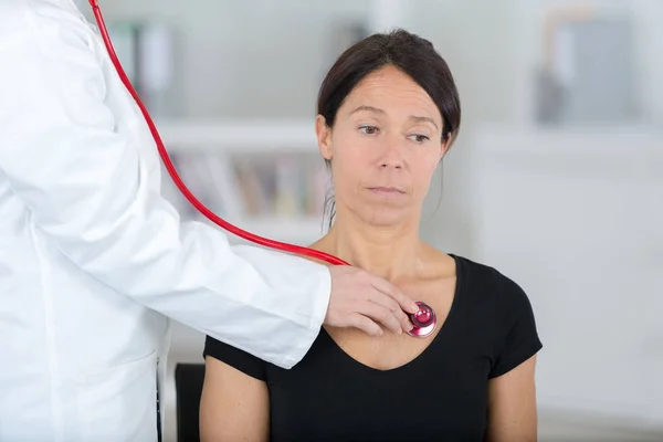 Женщина-врач осматривает пациента стетоскопом — стоковое фото