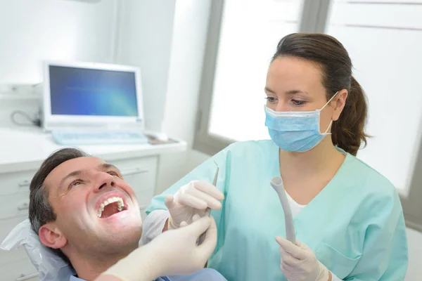 Жіночі стоматологи вивчають і працюють на пацієнта чоловічої статі — стокове фото