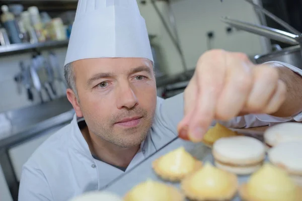 Chef pâtissier tenant délicieux gâteaux et pâtisseries à la recherche — Photo