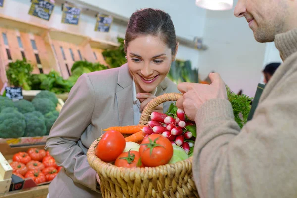 Mulher sorridente escolhendo frutas diferentes na exibição da loja de alimentos da fazenda — Fotografia de Stock