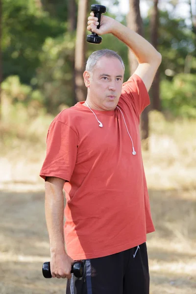 中年の男性が公園でダンベル運動 — ストック写真