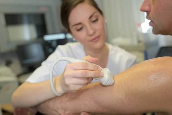 Médico femenino con paciente masculino sometido a ecografía de brazo —  Fotos de Stock