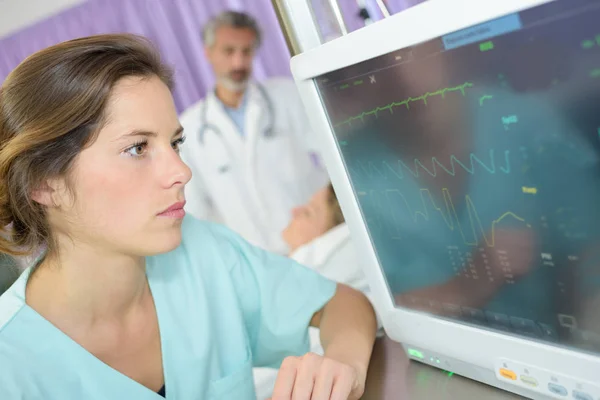 Nurse checking cardiogram report from electrocardiograph — Stock Fotó