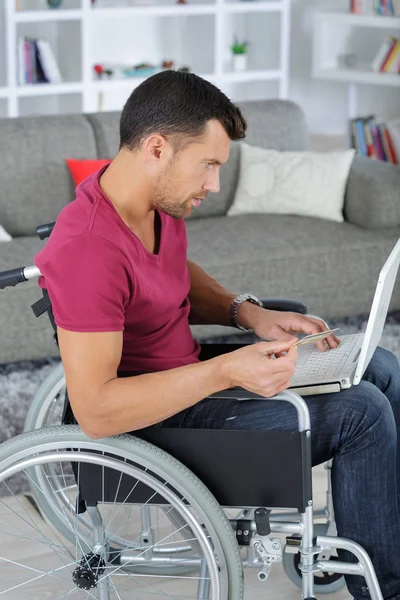 Gehandicapte Man In de rolstoel met behulp van Laptop thuis — Stockfoto