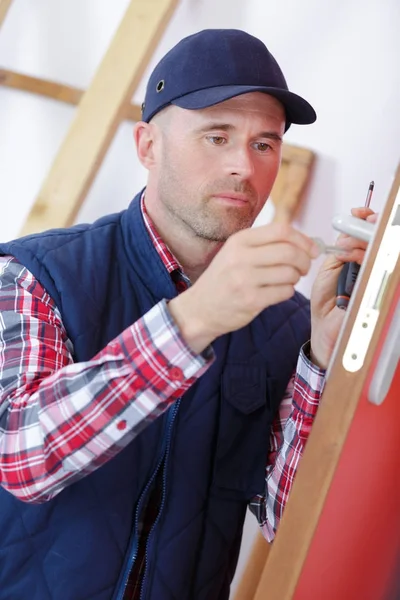 Masculino instalar fechadura da porta na porta usando chave de fenda sem fio — Fotografia de Stock