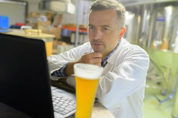 Hombre en cervecería mirando portátil — Foto de Stock