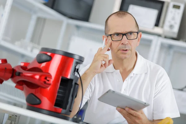 Tekniker på telefonen försöker fixa vakuum cleaner — Stockfoto