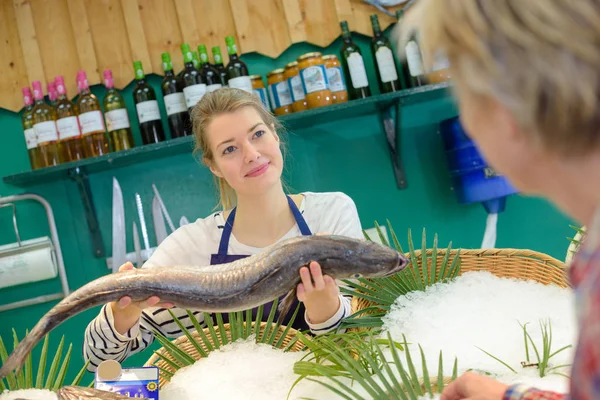 Verkäuferin hält Fisch vor Kunden — Stockfoto