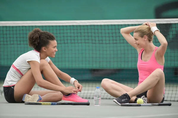 Donne seduti sul pavimento del campo da tennis — Foto Stock