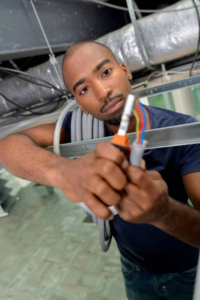 Mann im Dachraum hält Kabel und Prüfgerät — Stockfoto