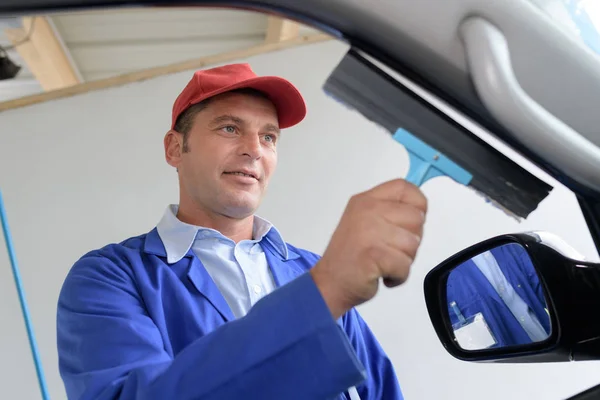 Hombre lavando ventana de coche con escobilla — Foto de Stock