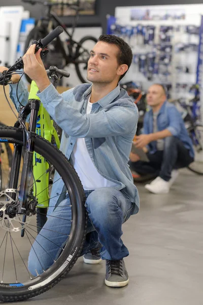 Mężczyzna sprawdza rower przed zakupem w sklepie sportowym — Zdjęcie stockowe