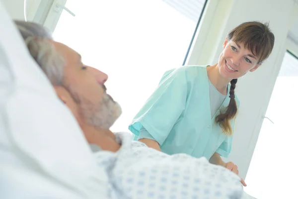 Медсестра посміхається чоловічому пацієнту — стокове фото