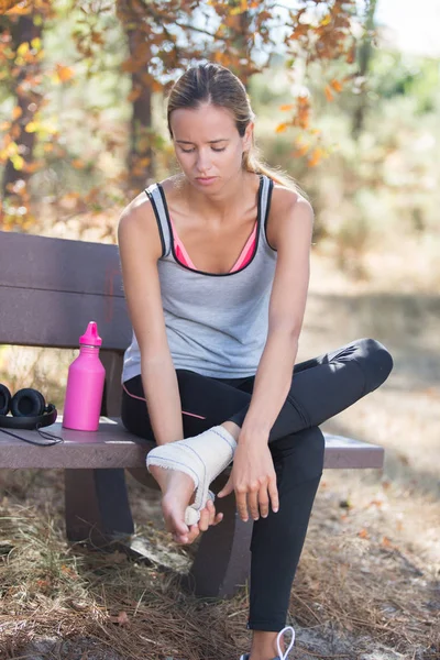Femme appliquant un bandage de compression sur sa jambe — Photo
