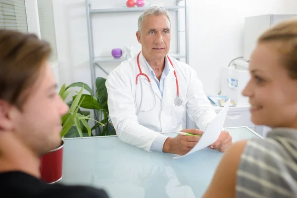 Dokter geven van goed nieuws aan jong koppel — Stockfoto