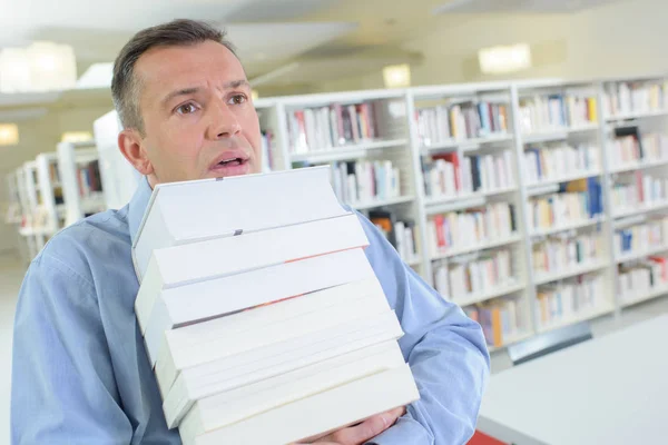 Бизнесмен борется держа много книг хотят быть повышены — стоковое фото