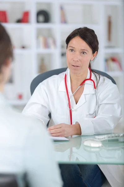 Hermosa doctora en bata blanca está hablando con paciente —  Fotos de Stock