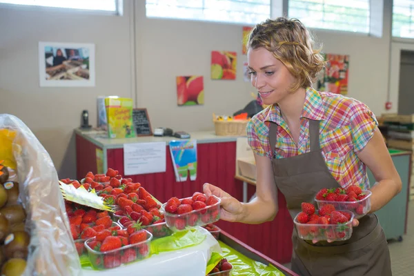 Frau räumt Erdbeerabteilung auf einem Markt auf — Stockfoto