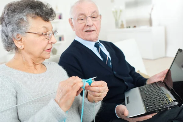 Anciano usando laptop, mujer tejiendo —  Fotos de Stock