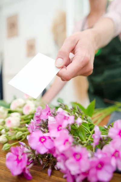 Ανθοπωλείο κρατώντας την κάρτα που θα συνοδεύει τα λουλούδια — Φωτογραφία Αρχείου