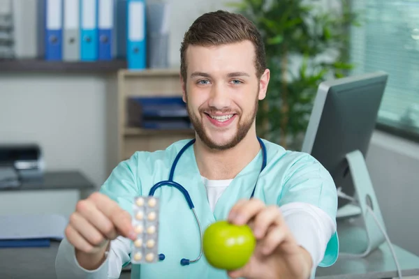 Médico mostrando maçã e pílulas — Fotografia de Stock