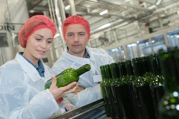 Mulher na fábrica segurando garrafa de vinho vazia — Fotografia de Stock