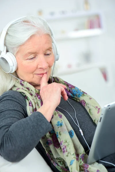 Mujer mayor feliz escuchando música en una tableta digital —  Fotos de Stock