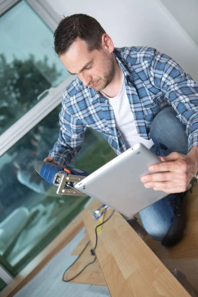 Carpenter cutting wood while checking tablet — Stock Photo, Image