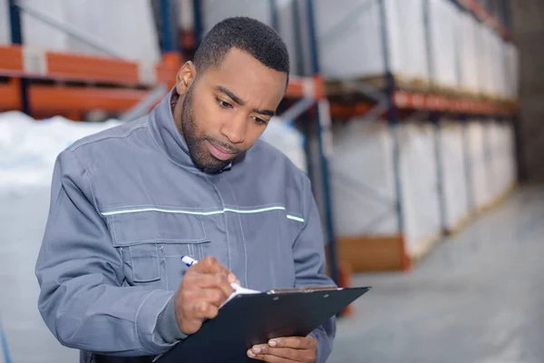 Trabajador de almacén escribiendo una investigación — Foto de Stock