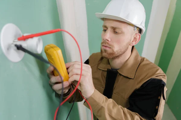 Elettricista controllo tensione presa con multimetro digitale — Foto Stock