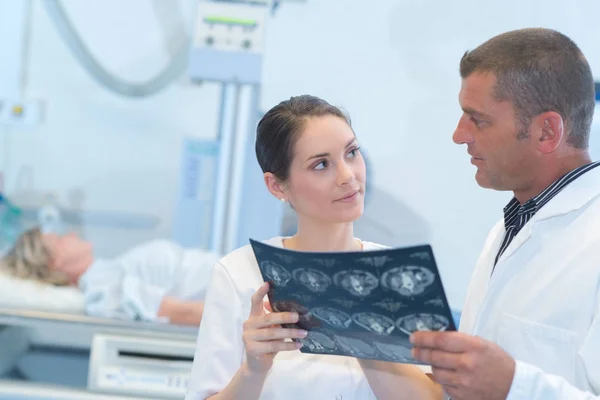 Médico masculino y femenino que mira la radiografía del paciente en el lugar de trabajo — Foto de Stock