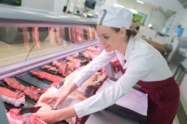 Feliz carnicero femenino en el mostrador de la tienda de carne — Foto de Stock