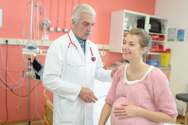 Retrato de médico examinando e dando fisioterapia à mulher grávida — Fotografia de Stock