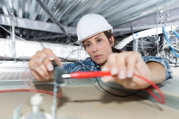 Kadın elektrikçi tavana elektrikli cihaz yerleştiriyor — Stok fotoğraf