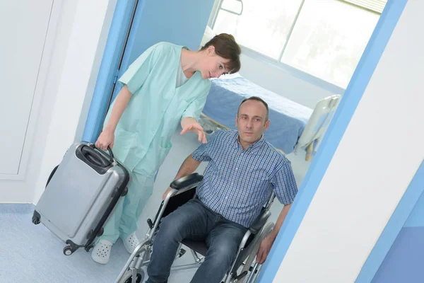 Людина в інвалідному візку залишає лікарню — стокове фото