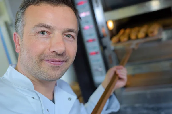 Пекарь получает свежий хлеб из традиционной духовки — стоковое фото