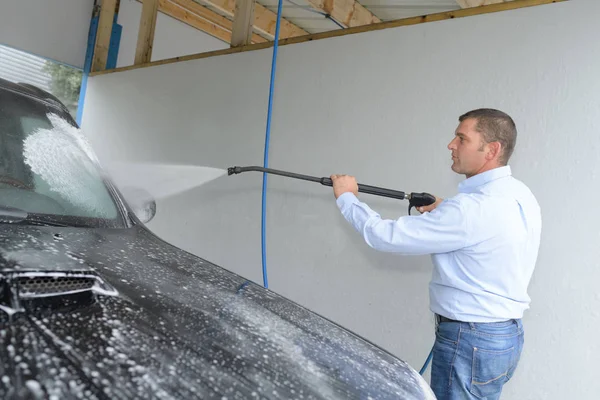 Hombre de limpieza de un coche con agua de pulverización — Foto de Stock